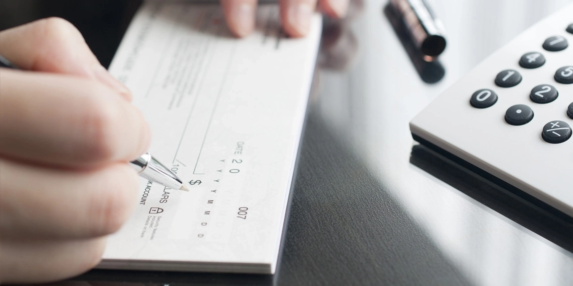 Close up of two hands writing on the check